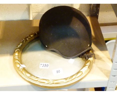Circular bulls eye mirror in brass coloured frame and a riding helmet