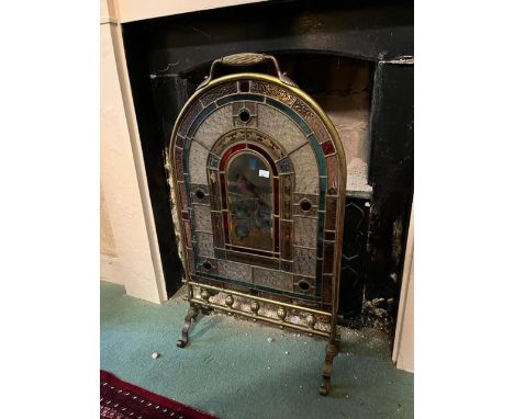 An arch top brass cheval Firescreen, with leaded and coloured glass panel, the centre painted with a robin perched on a tree 