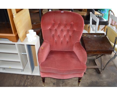 A pink upholstered button back arm chair 