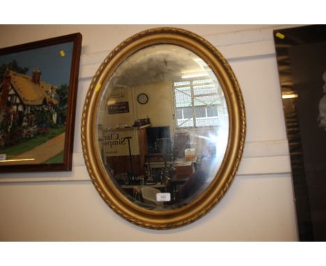 A gilt framed oval and bevel edged mirror 