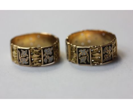 A pair of unmarked yellow metal flat section rings with black and white enamel decoration, 5.9g