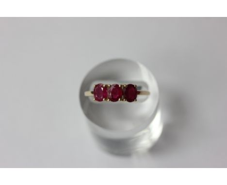 A ruby three stone ring set with graduated oval cuts in 10ct gold