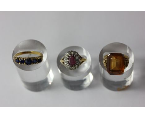 A ruby and diamond cluster ring the oval cut stone in 18ct gold; a sapphire four stone ring; and a citrine dress ring in plat