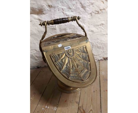 A 19th Century brass coal scuttle of lift-top helmet form with embossed floral decoration, integral scoop and turned wood han