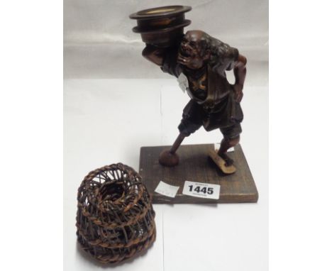 A Japanese Meiji period bronze figural candlestick depicting a sailor with later adapted replacement wooden leg, set on woode