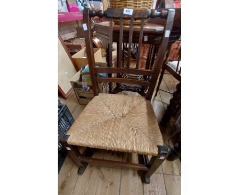 An old stained beech framed stick back rocking chair with woven rush seat