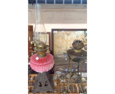 A Victorian oil lamp with a moulded cased cranberry opaque glass reservoir, set on a decorative cast iron base, with glass ch