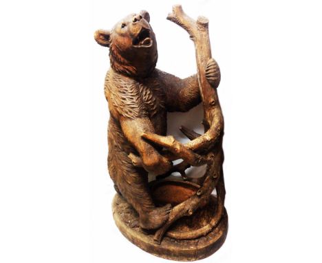 A 1.15m high antique Black Forest carved wood stick stand in the form of a large brown bear hugging a branching tree trunk wi