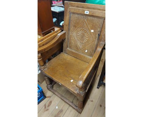 A 19th Century oak wainscot chair with carved back panel, open armrests and solid seat, set on turned front supports