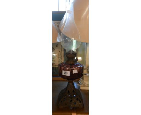 A late 19th Century oil lamp with amethyst glass reservoir set on a cast iron base, with glass chimney