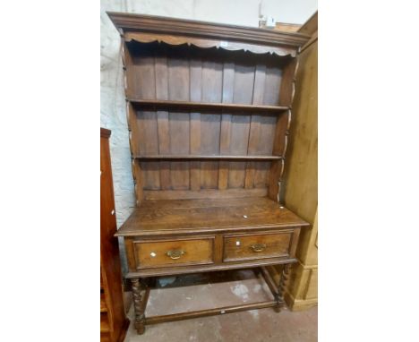 A 1.06m old oak dresser in the antique style with two shelf open plate rack over a base with two short drawers, set on an ope