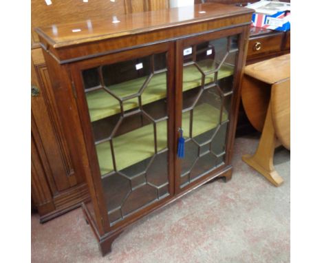 An 84cm early 20th Century stained walnut book cabinet with material lined shelves enclosed by a pair of astragal glazed cupb