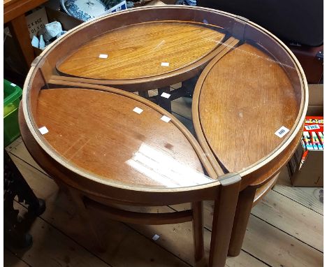 An 80cm diameter vintage Nathan 'Trinity' glass topped coffee table with three nesting elliptical tea table, set on moulded s