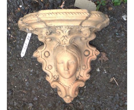 A small terracotta wall shelf with female mask decoration