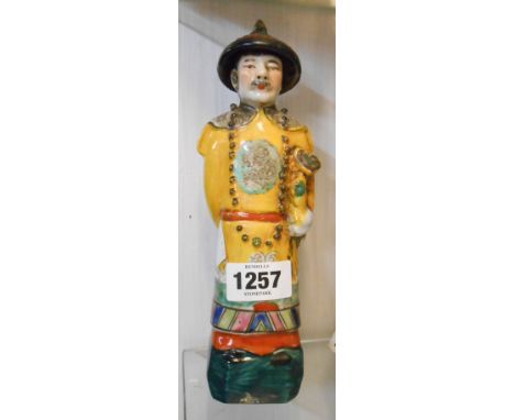 A Chinese porcelain figurine, depicting a man wearing yellow robes with coloured enamel - impressed seal mark to base