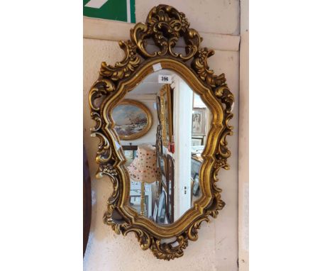 A vintage ornate gilt plaster framed Rococo style wall mirror with pierced foliate scroll border