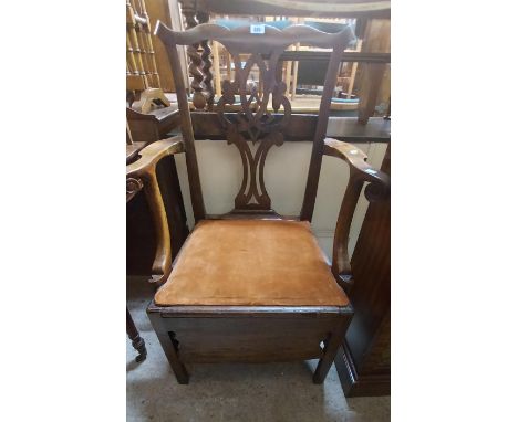 An antique mahogany framed Chippendale style commode elbow chair with upholstered drop-in seat and shaped apron, set on chamf