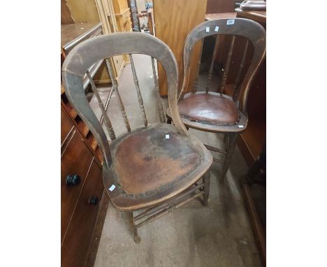 A pair of late Victorian oak framed spindle back chairs with studded rexine seat panels, set on turned front supports - wear