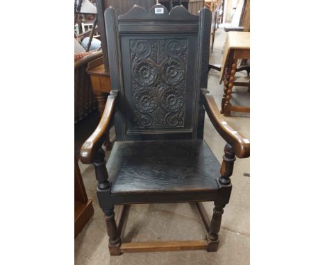 A 19th Century carved oak wainscoat chair with decorative floral roundel back panel, open armrests and solid seat, set on tur