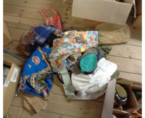 A box containing a quantity of vintage clothing and textiles including pillbox hats, tea cosies, embroidered panels, Victoria