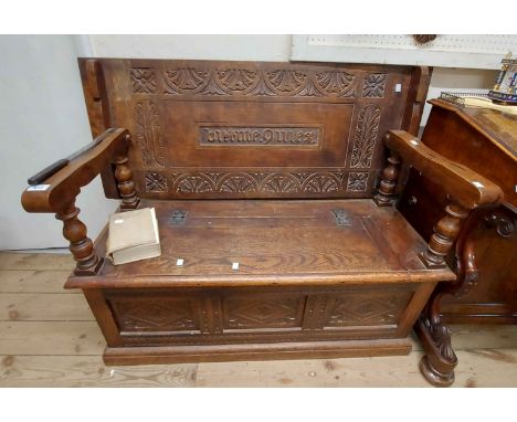 A 1.1m late Victorian carved oak monk's bench with central text panel 'Virtute Quies' (In Virtue There is Rest) within a deco