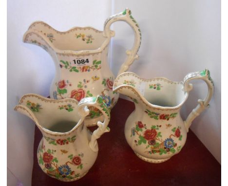 A set of three 19th Century graduated jugs of helmet form with floral decoration