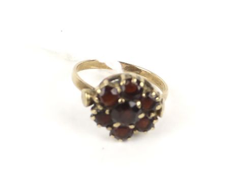 An early 20th century rose gold and garnet cluster ring. The seven round mixed-cut stones all claw set on a D-section shank s