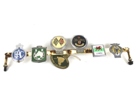 Seven vintage car badges. Including a ARC badge, AA badge, etc. all mounted onto a metal bar, L70cm