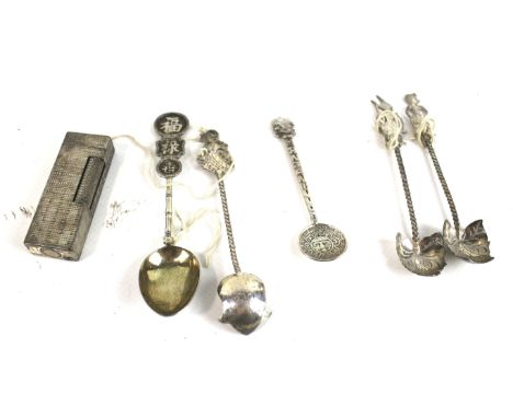 A Dunhill lighter and five white metal spoons. The lighter with textured decoration, three of the spoons topped with deities