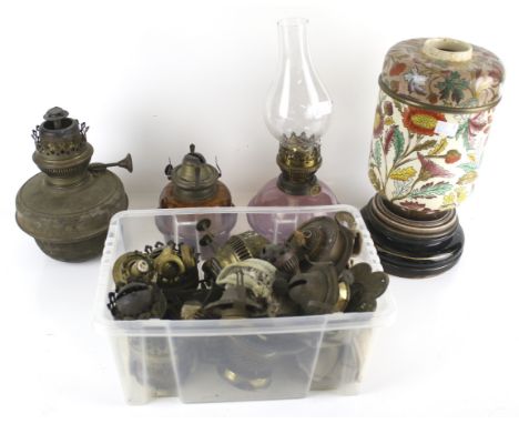 An assortment of 19th century and later oil lamp components. Including a floral ceramic base, burners, reservoirs, flutes, et