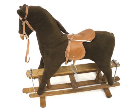 A vintage rocking horse. The horse constructed of brown fleece, wearing a brown leather saddle, mounted on a wooden stand, H1