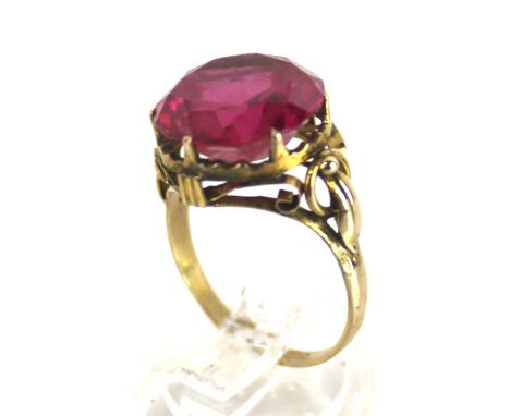 A far Eastern synthetic ruby single stone ring. The round stone approx. 13mm diameter, claw set between open leaf and hoop sh