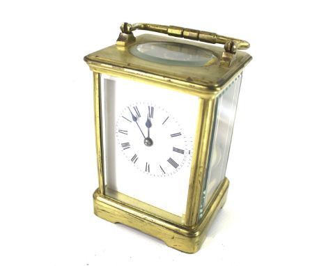 A carriage clock. The white enamel dial with Roman numerals, with a brass case topped with a carry handle, H15cm