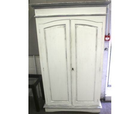 A large 20th century wardrobe. Painted white, the panelled doors opening to reveal two drawers and a shelf (the clothing rail