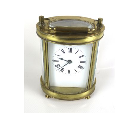 A 20th century English carriage clock. The white enamel dial with Roman numerals, within an oval brass case with a handle to 