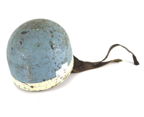 A vintage motorcycle helmet. Painted blue and white with the number '1', lined with brown leather padding with a chin strap, 