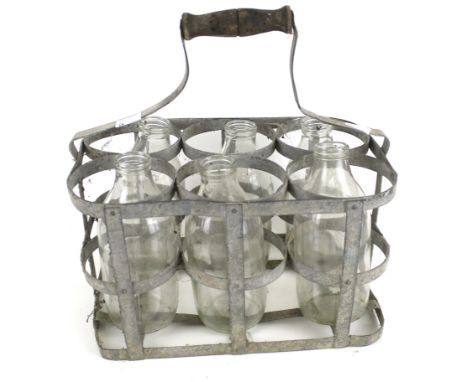 A vintage milk bottle carrier and six glass bottles. With a turned wooden handle, H30cm