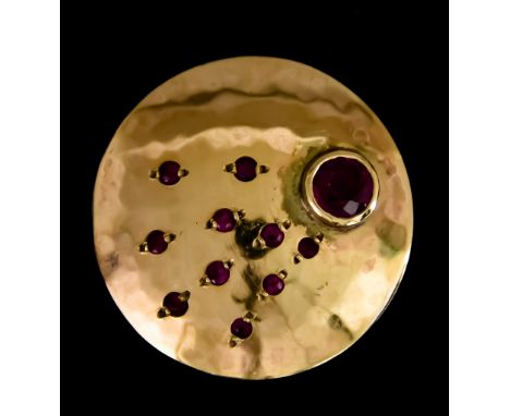 A Ruby Set Disc Pendant, set with one large ruby, approximately .50ct, and ten other small graduated rubies, 26mm in diameter