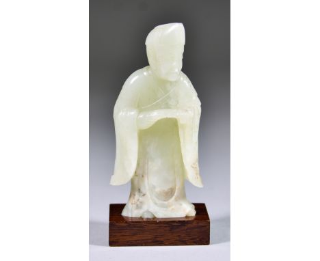 A Chinese Celadon Jade Figure of a Daoist Immortal, 19th Century, 4.25ins (10.9cm) high, and a hardwood standImages within at