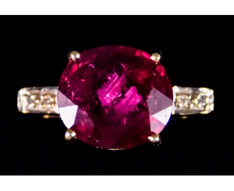 An 18ct Gold Ruby and Diamond Ring, set with a centre faceted ruby, approximately 9.4ct, flanked by small brilliant cut diamo