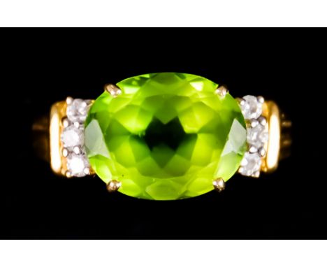 An 18ct Gold Peridot and Diamond Ring, set with a centre peridot, approximately 6.7ct, flanked by small brilliant cut white d