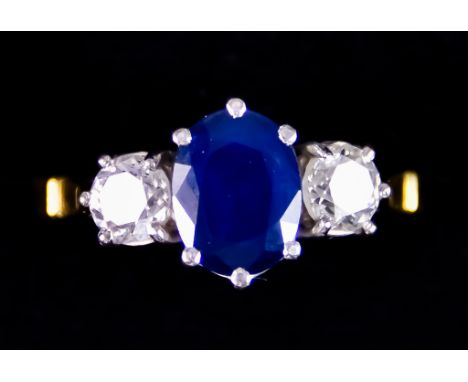 An 18ct Gold Three Stone Sapphire and Diamond Ring, set with a centre sapphire, approximately 1ct, flanked by two brilliant c