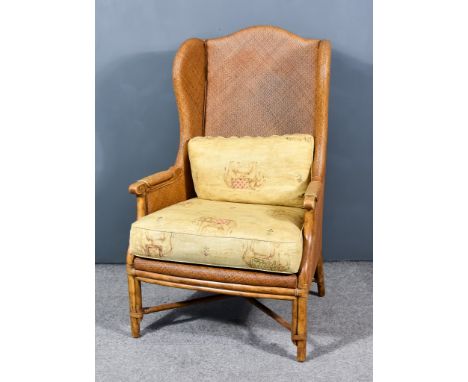 A Rattan Wingback Armchair of "Georgian" Design, upholstered in wicker and on bamboo supportsSome light scattered scratching 