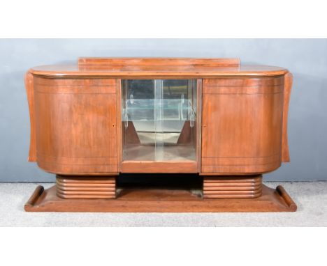 An Early 20th Century Walnut Oval Side Cabinet of Art Deco Design, with moulded edge to top, fitted one shelf enclosed by sli