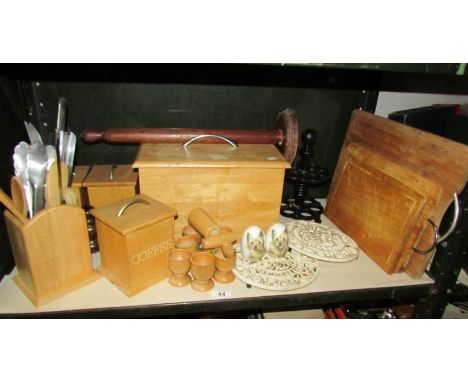 A shelf of kitchen ware including bread bin, chopping boards etc.,