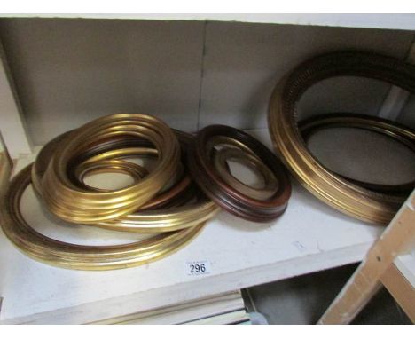 A shelf of gilded and other oval picture frames.