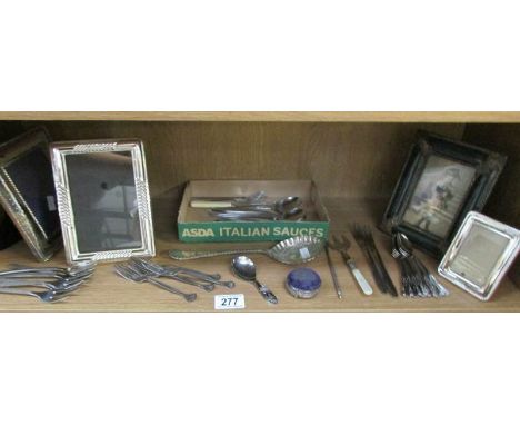 A shelf of cutlery and photo frames.