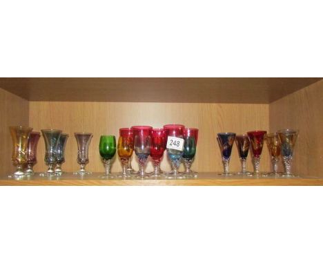 A shelf of coloured liquor glasses.