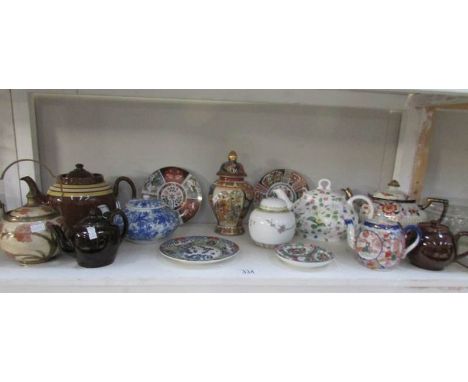 A shelf of tea ware including oriental teapots etc.,