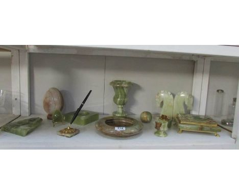 A shelf of onyx items including book ends, ash trays, urn, pen stand etc.,